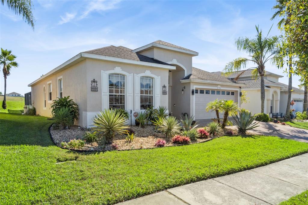 A single-story suburban house with a beige stucco exterior, a two-car garage, and landscaping — 722 BIRKDALE STREET, DAVENPORT, FL
