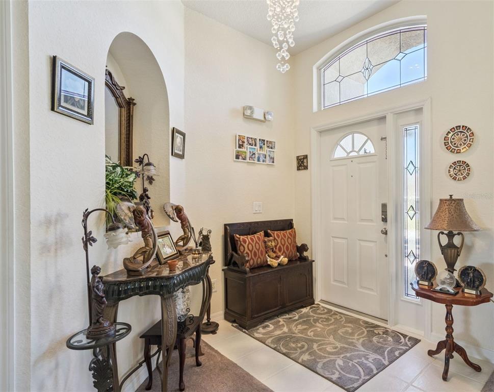 A high-ceilinged entryway features a white front door, a wooden bench, and decorative furniture — 722 BIRKDALE STREET, DAVENPORT, FL