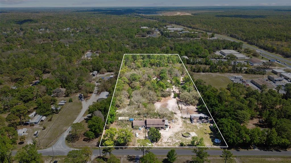 An aerial view shows a house and outbuildings on a large, wooded, rectangular lot — 589 S LEONA AVENUE, LECANTO, FL