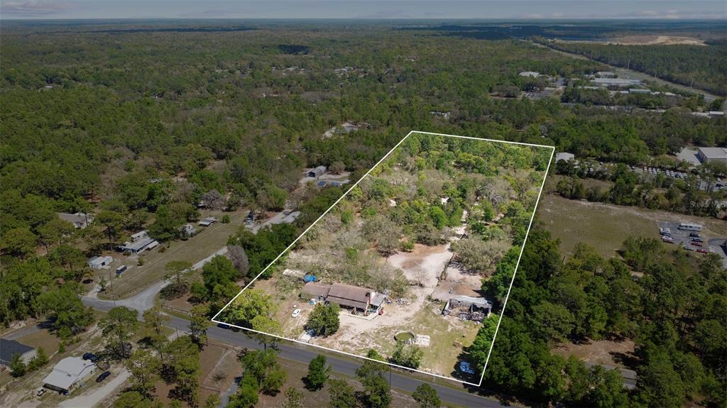 An aerial view shows a house and outbuilding on a large, wooded, rectangular lot — 589 S LEONA AVENUE, LECANTO, FL