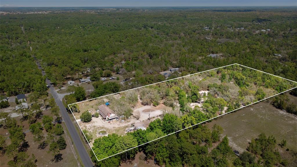 An aerial view shows a house on a large, wooded lot bordered by a road — 589 S LEONA AVENUE, LECANTO, FL