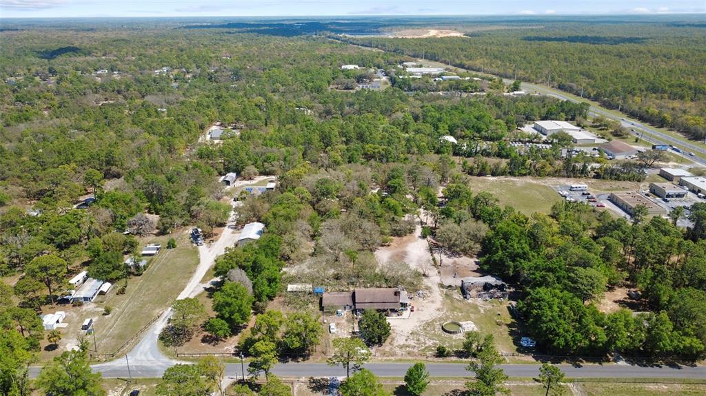 An aerial view shows a rural property with a house, outbuildings, and surrounding wooded land — 589 S LEONA AVENUE, LECANTO, FL
