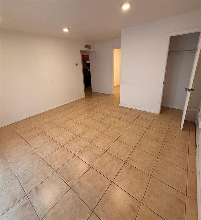 An empty room with beige tile flooring, white walls, and two doorways — 6519 W NEWBERRY ROAD UNIT 604, GAINESVILLE, FL