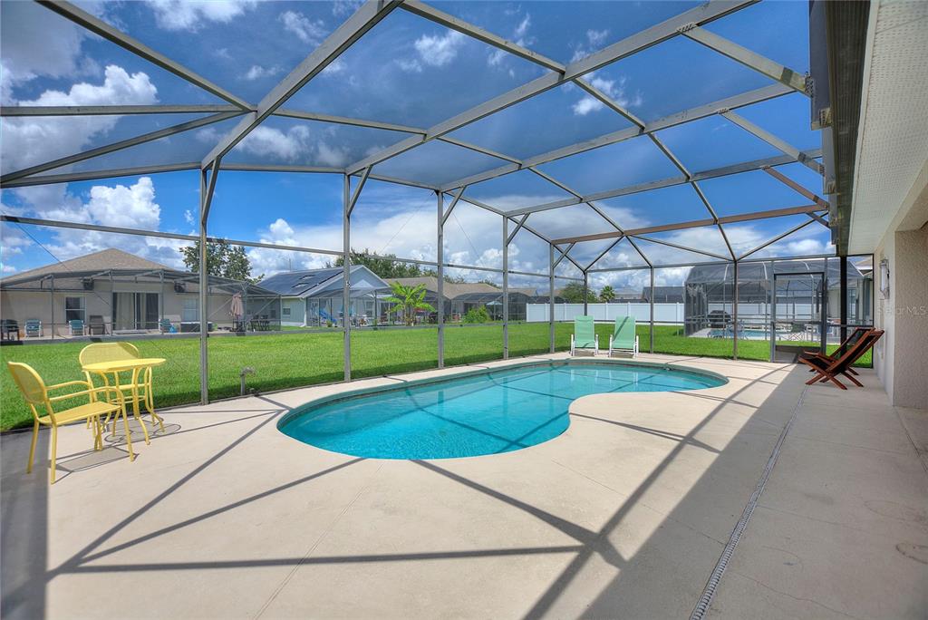 A swimming pool with a screened enclosure sits on a concrete patio in a backyard — 2705 PRESTWICK LANE, KISSIMMEE, FL
