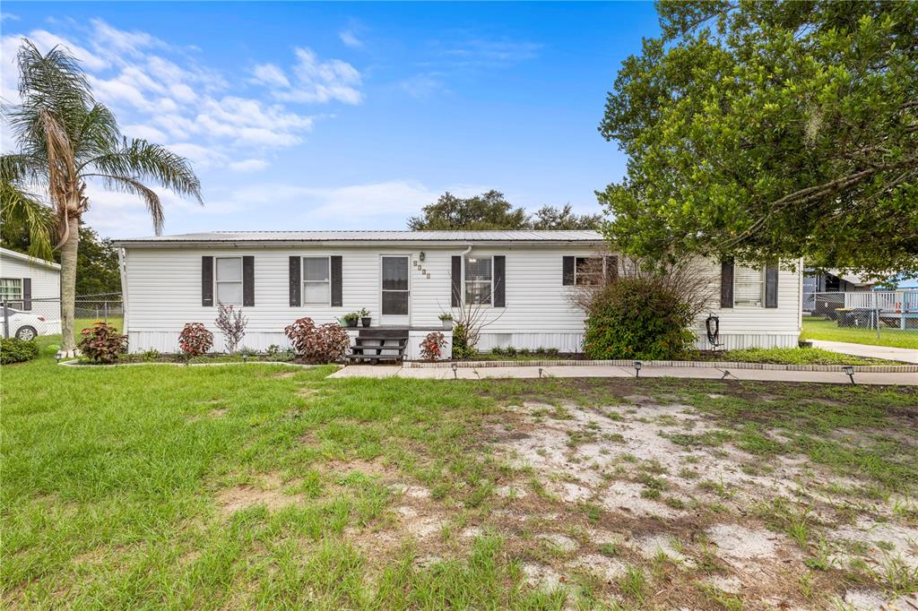 A single-story white mobile home with a metal roof and a front lawn — 4332 UPPER MEADOW ROAD, MULBERRY, FL
