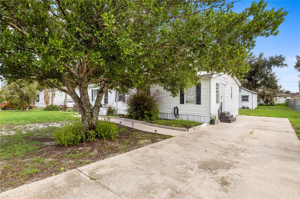 A white mobile home with a concrete driveway and a large tree in the front yard — 4332 UPPER MEADOW ROAD, MULBERRY, FL
