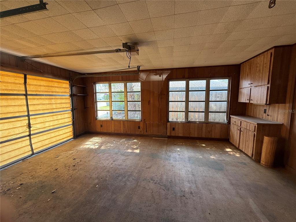 A garage with wood-paneled walls, a concrete floor, and built-in wooden cabinets — 22 BIRDIE DRIVE, NEW SMYRNA BEACH, FL