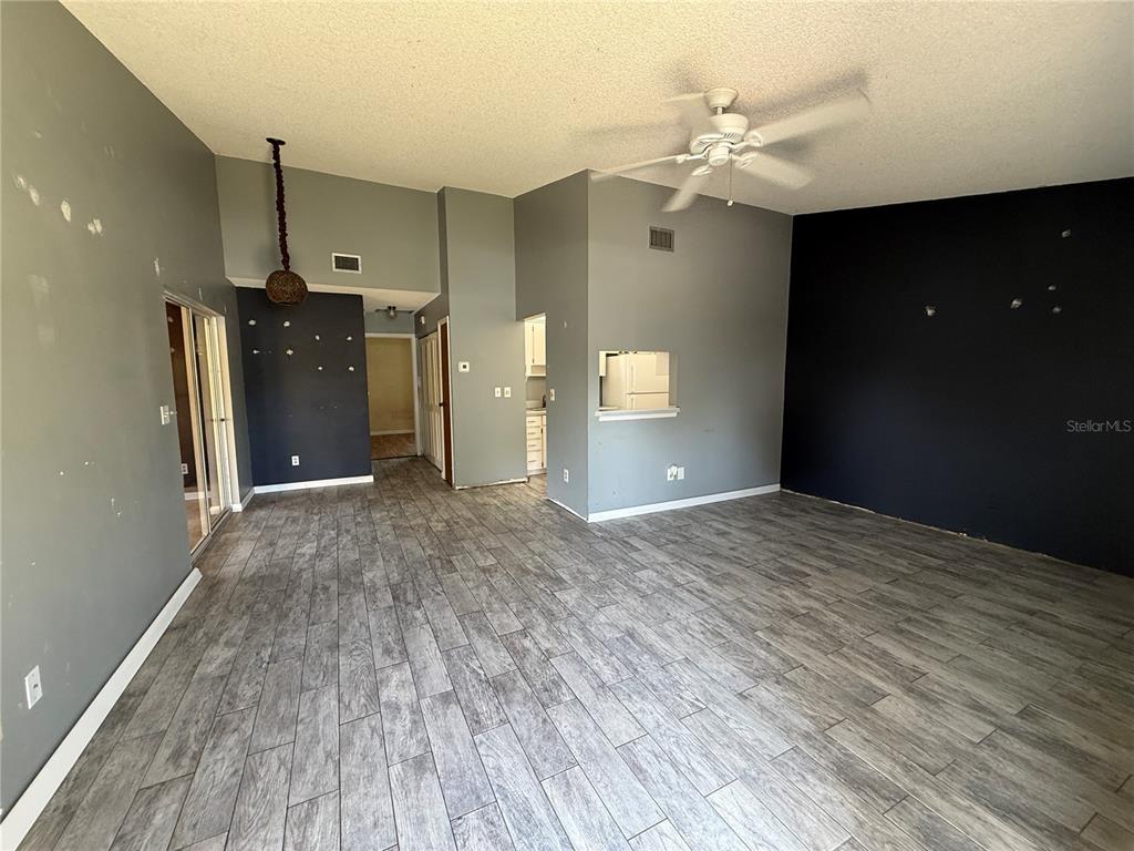 An open-concept living room features gray walls, a dark accent wall, and wood-look tile flooring — 22 BIRDIE DRIVE, NEW SMYRNA BEACH, FL