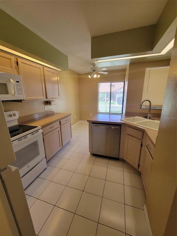 A kitchen with light wood cabinets, white appliances, tile flooring, and a window over the sink — 3333 GRAY FOX COVE UNIT 3333, APOPKA, FL