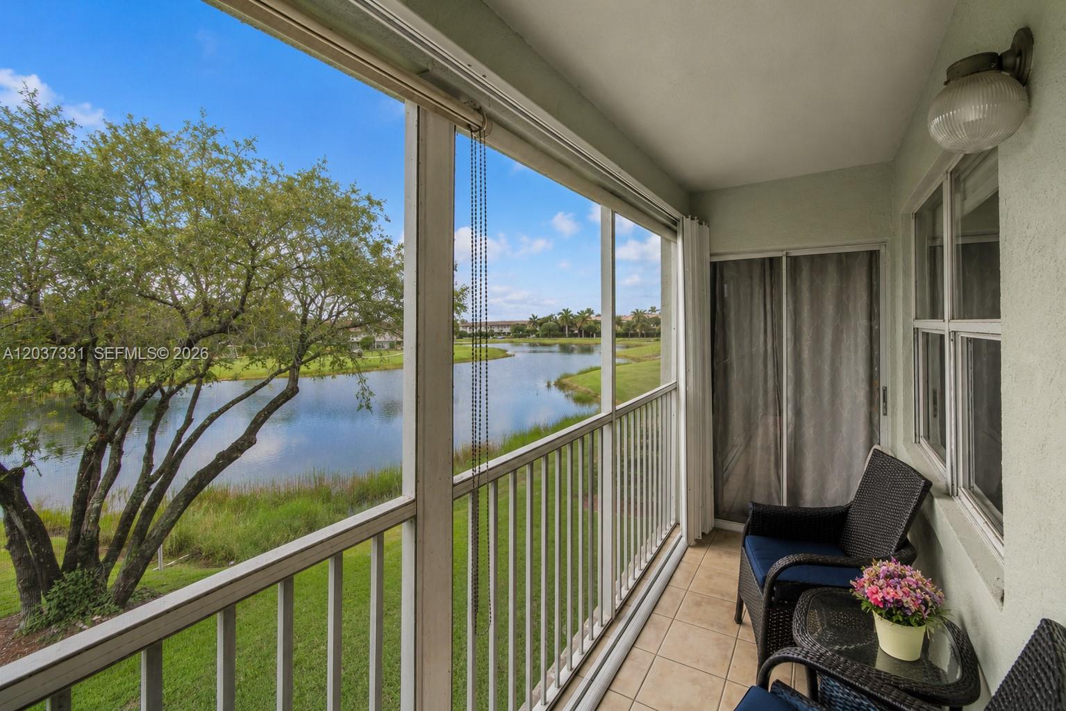 A screened-in balcony features tile flooring, wicker furniture, and a view of a lake — 2518 SE 20th Pl # B, Homestead FL 33035, HOMESTEAD, FL