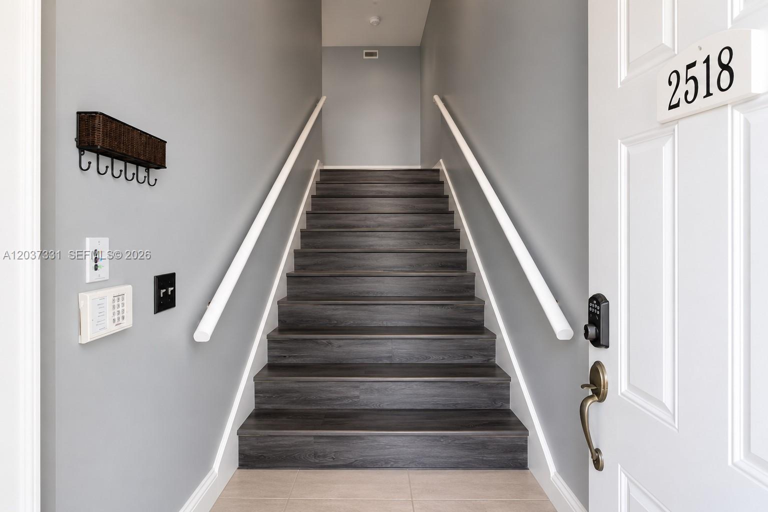 A staircase with dark wood-look steps leads upward between two gray walls — 2518 SE 20th Pl # B, Homestead FL 33035, HOMESTEAD, FL
