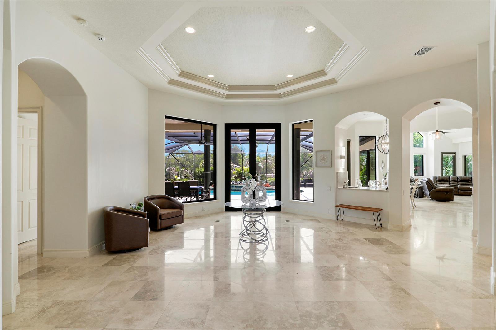 A spacious foyer with marble floors, a tray ceiling, and a view of the pool — 18989 SE Windward Island Lane, Jupiter FL 33458, JUPITER, FL