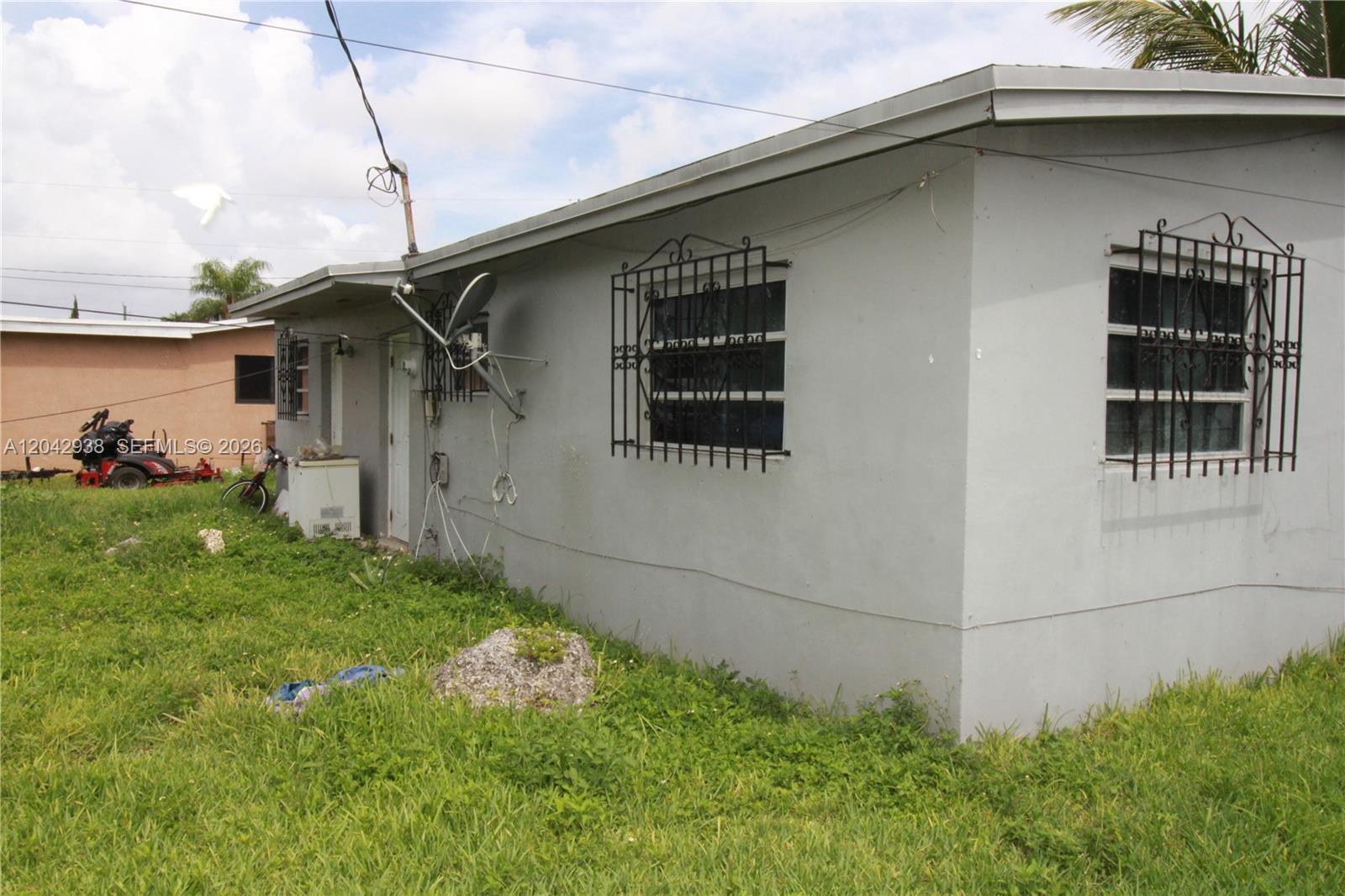 A gray, single-story house exterior features barred windows and a satellite dish — 10820 SW 220th St, Miami FL 33170, MIAMI, FL