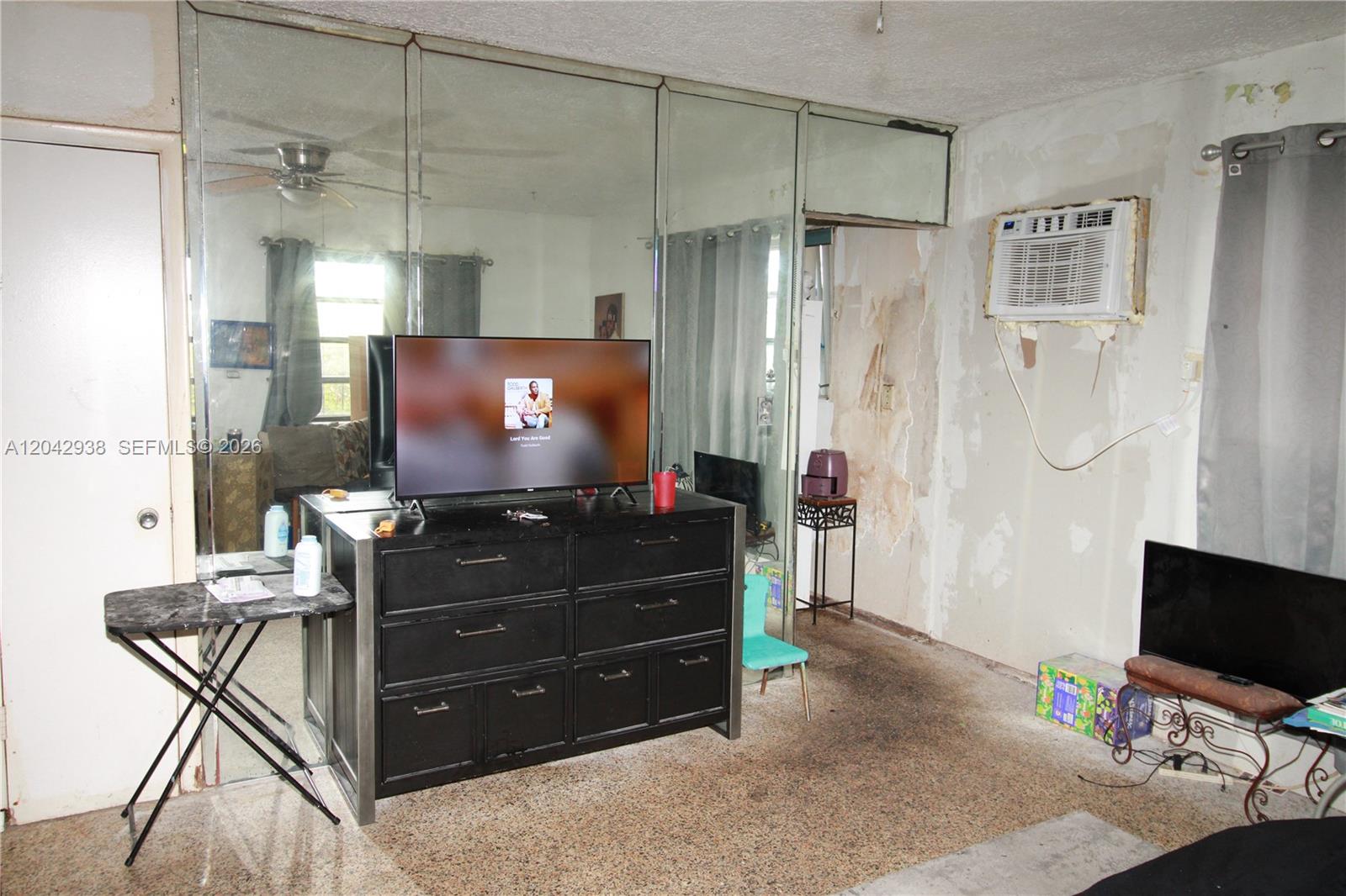A room features mirrored walls, a black dresser with a television, and a window air conditioner — 10820 SW 220th St, Miami FL 33170, MIAMI, FL