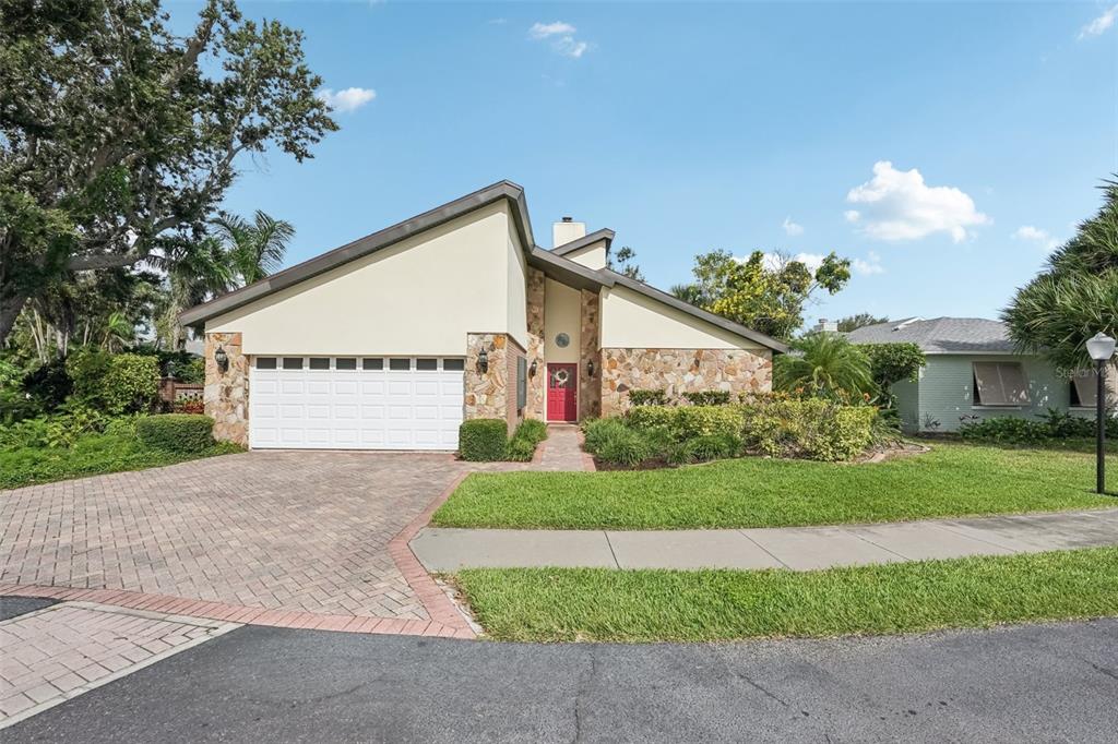 A single-story house with a stone facade, a red front door, and a paved driveway — 2312 89TH STREET NW UNIT 32, BRADENTON, FL
