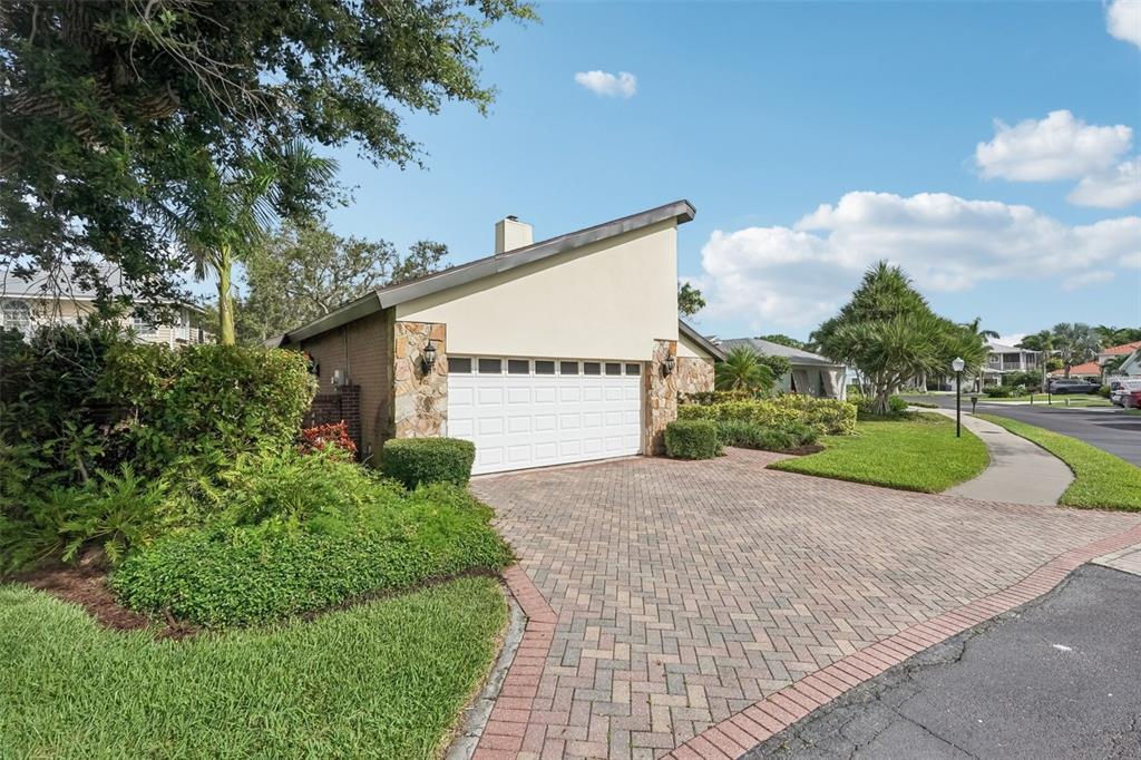 A single-story house with a white garage door, stone accents, and a paved driveway — 2312 89TH STREET NW UNIT 32, BRADENTON, FL
