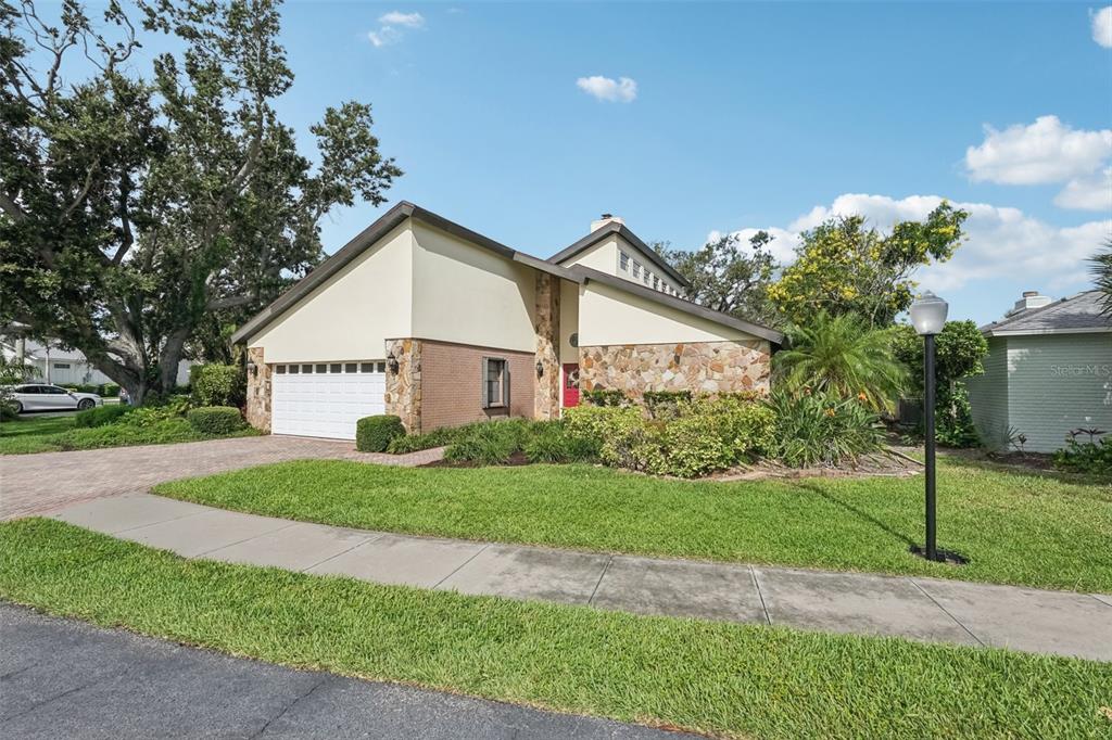 A two-story house with a stone facade, a white garage door, and a paved driveway — 2312 89TH STREET NW UNIT 32, BRADENTON, FL