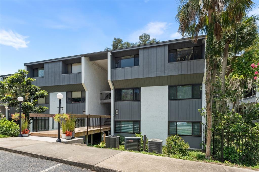 A multi-story apartment building features gray siding, white stucco walls, and an elevated wooden walkway — 2660 SW 14TH DRIVE UNIT 125, GAINESVILLE, FL