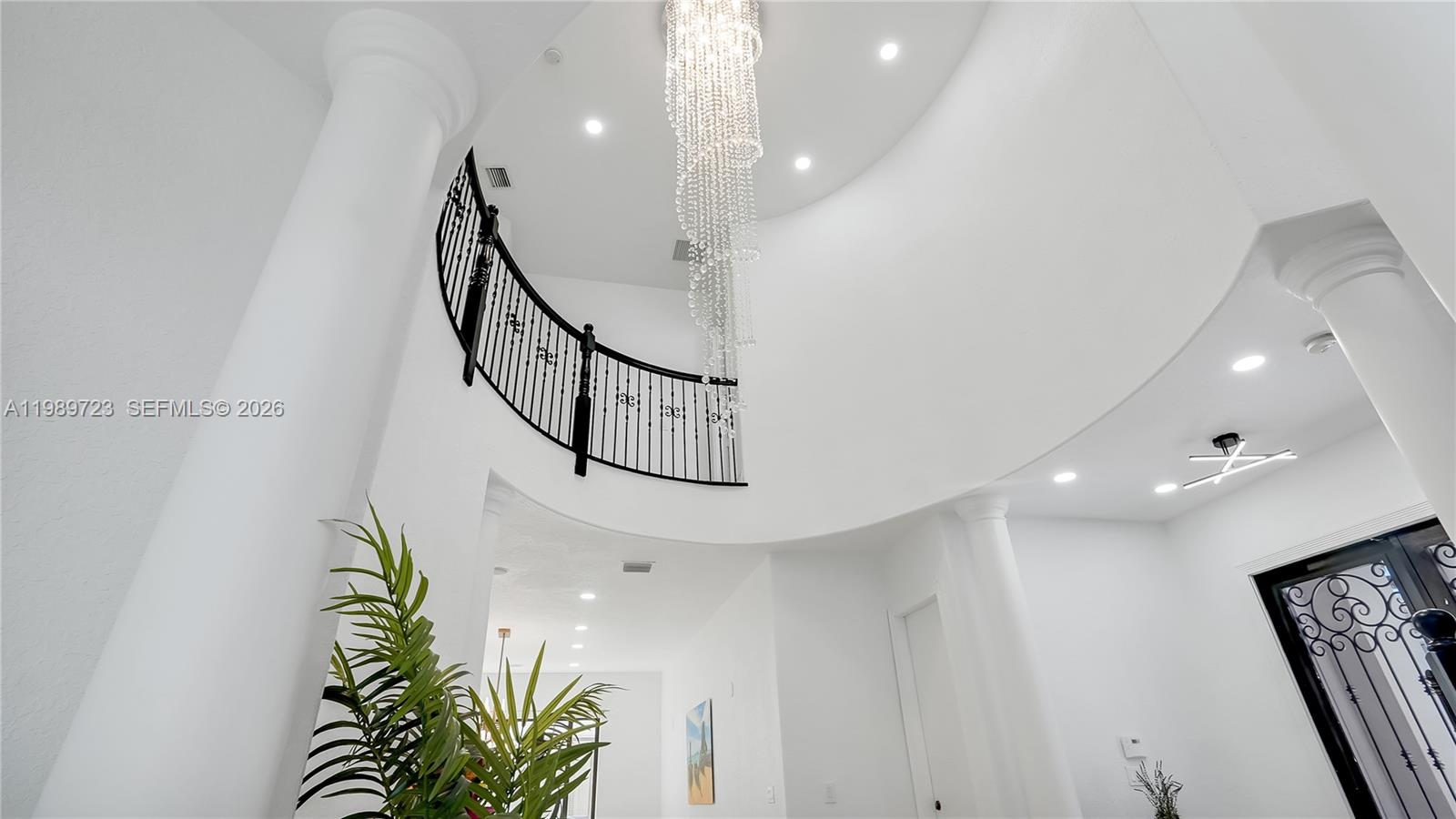 A grand foyer features a curved staircase, a crystal chandelier, and white columns — 7965 SW 195th St, Cutler Bay FL 33157, CUTLER BAY, FL