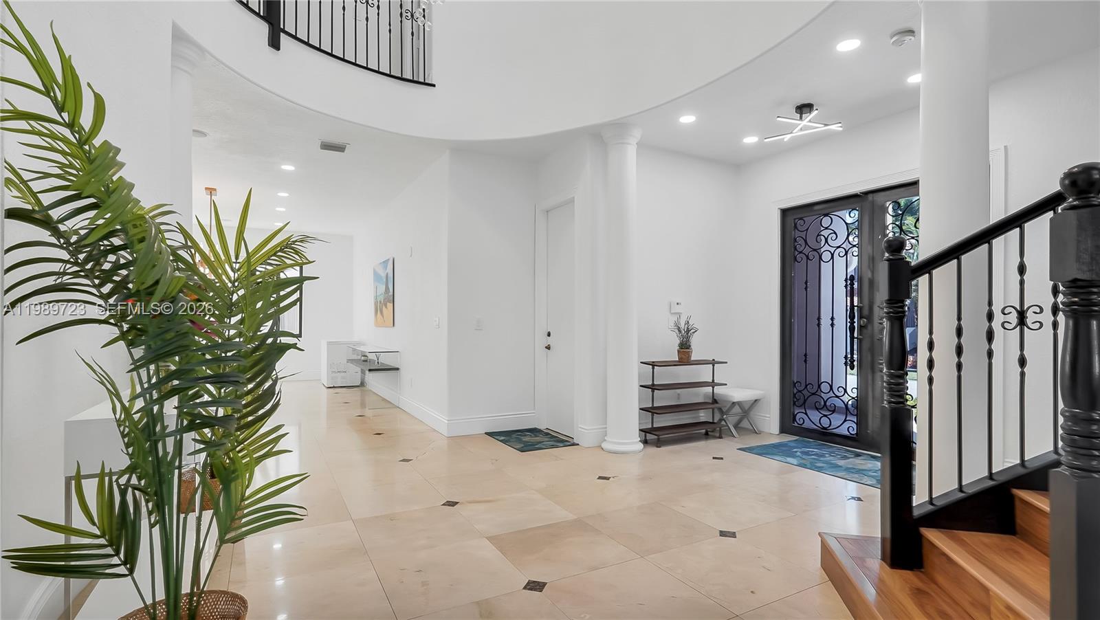 A bright, spacious foyer features light tile flooring, a curved staircase, and a decorative door — 7965 SW 195th St, Cutler Bay FL 33157, CUTLER BAY, FL