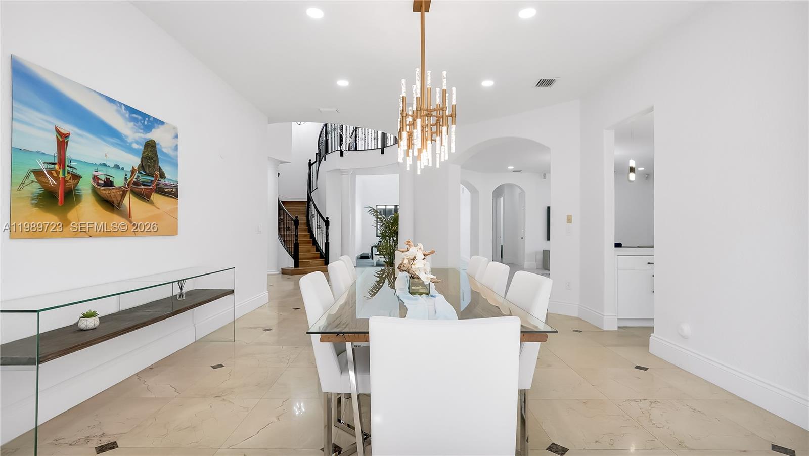 A dining room features a glass table, white chairs, a chandelier, and a curved staircase — 7965 SW 195th St, Cutler Bay FL 33157, CUTLER BAY, FL