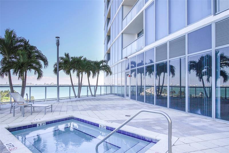 A hot tub sits on a paved terrace next to a modern building with glass walls — 601 NE 36th Street # 2806, Miami FL 33137, MIAMI, FL