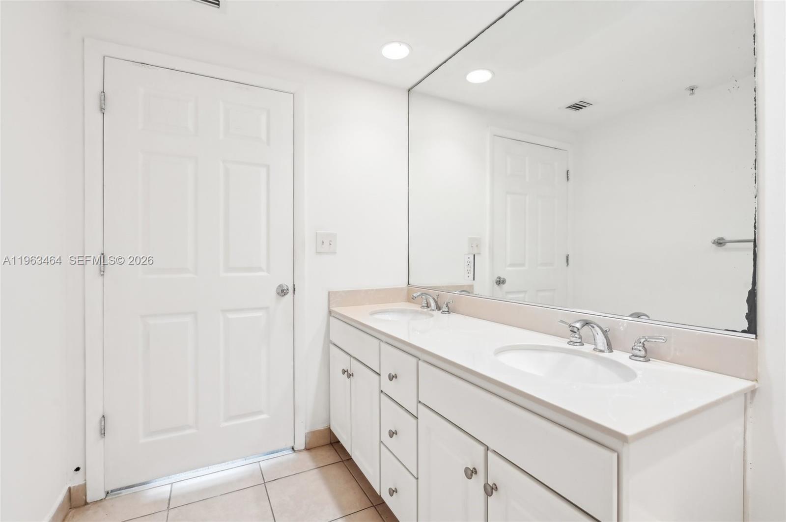 A bathroom features a double-sink vanity with white cabinets, a large mirror, and tiled flooring — 2000 N Bayshore Dr # 304, Miami FL 33137, MIAMI, FL