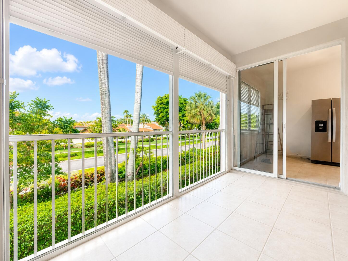 A tiled balcony with white railings overlooks a street with palm trees and houses — 6560 Villa Sonrisa Drive # 1321, Boca Raton FL 33433, BOCA RATON, FL