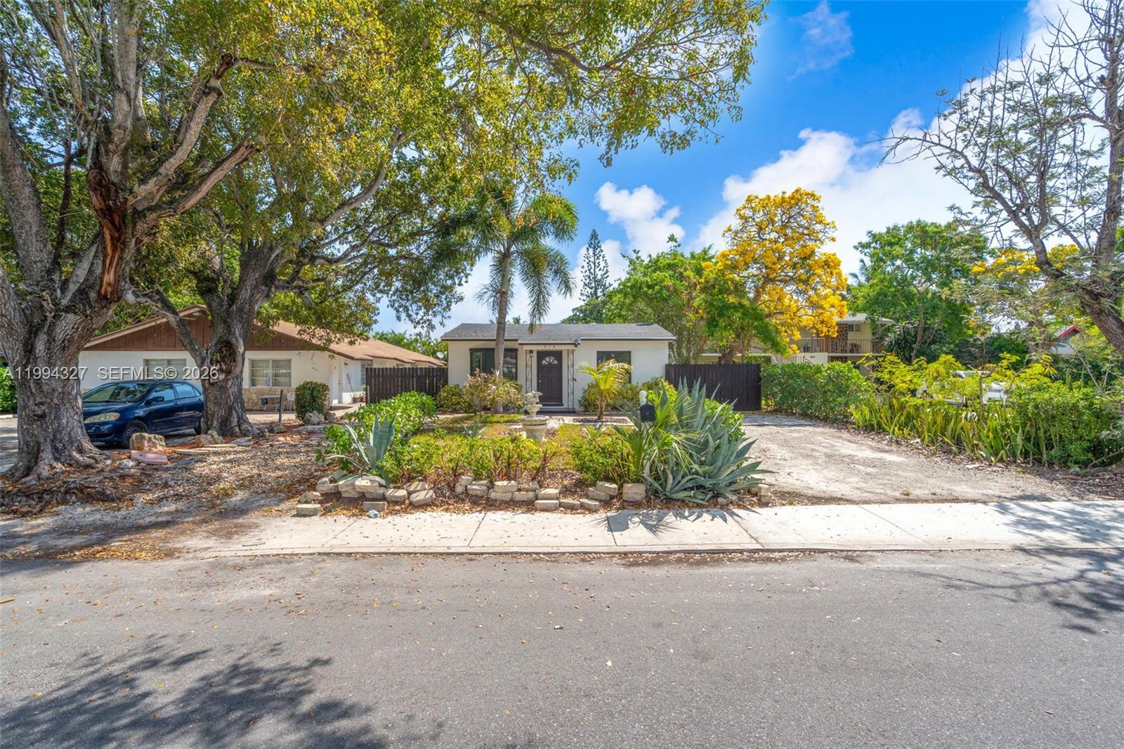 A single-story house with a front yard, a driveway, and large trees under a blue sky — 914 S L St, Lake Worth FL 33460, LAKE WORTH, FL