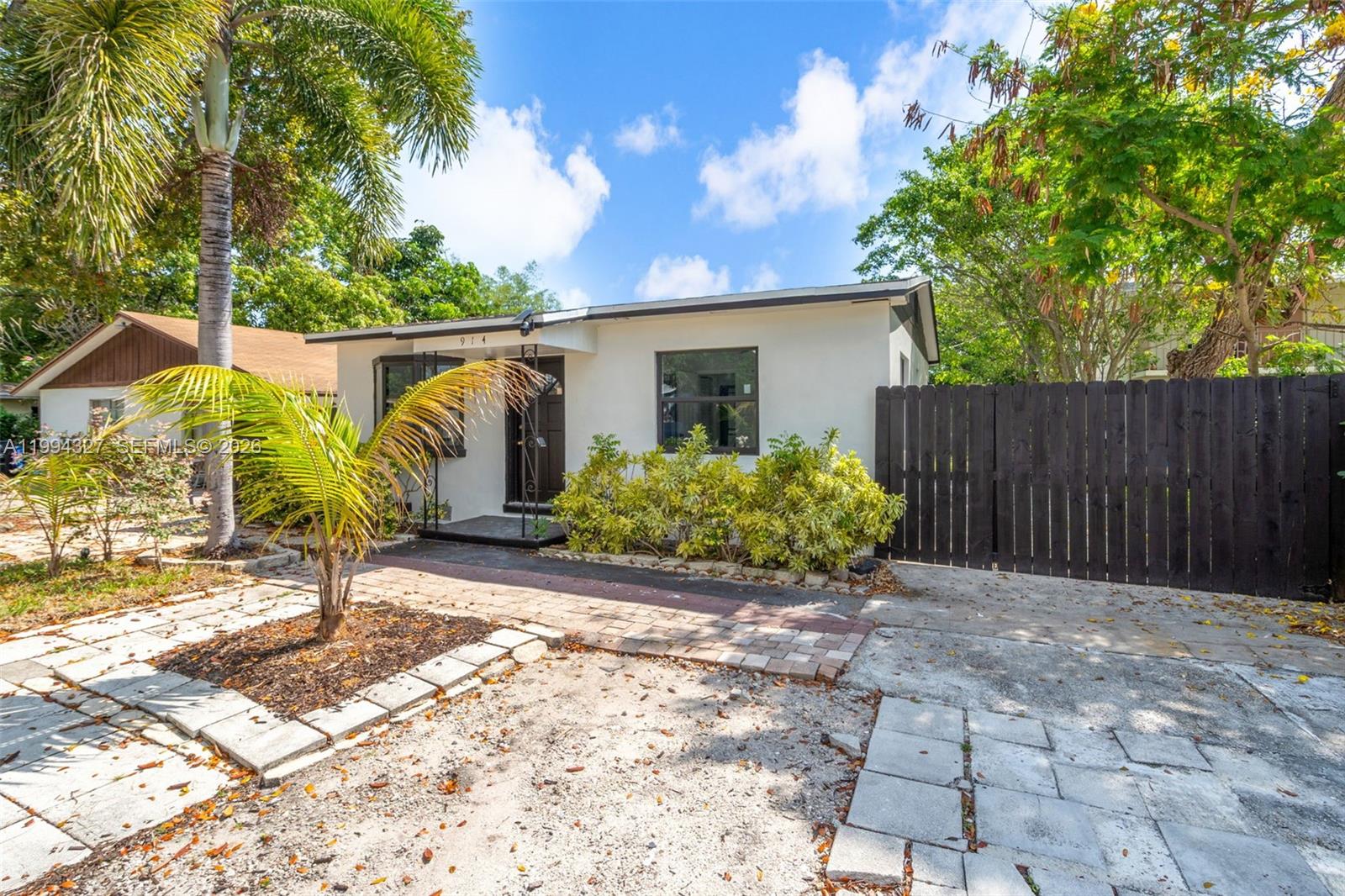 A single-story white house features a front entrance, a paved walkway, and a wooden fence — 914 S L St, Lake Worth FL 33460, LAKE WORTH, FL