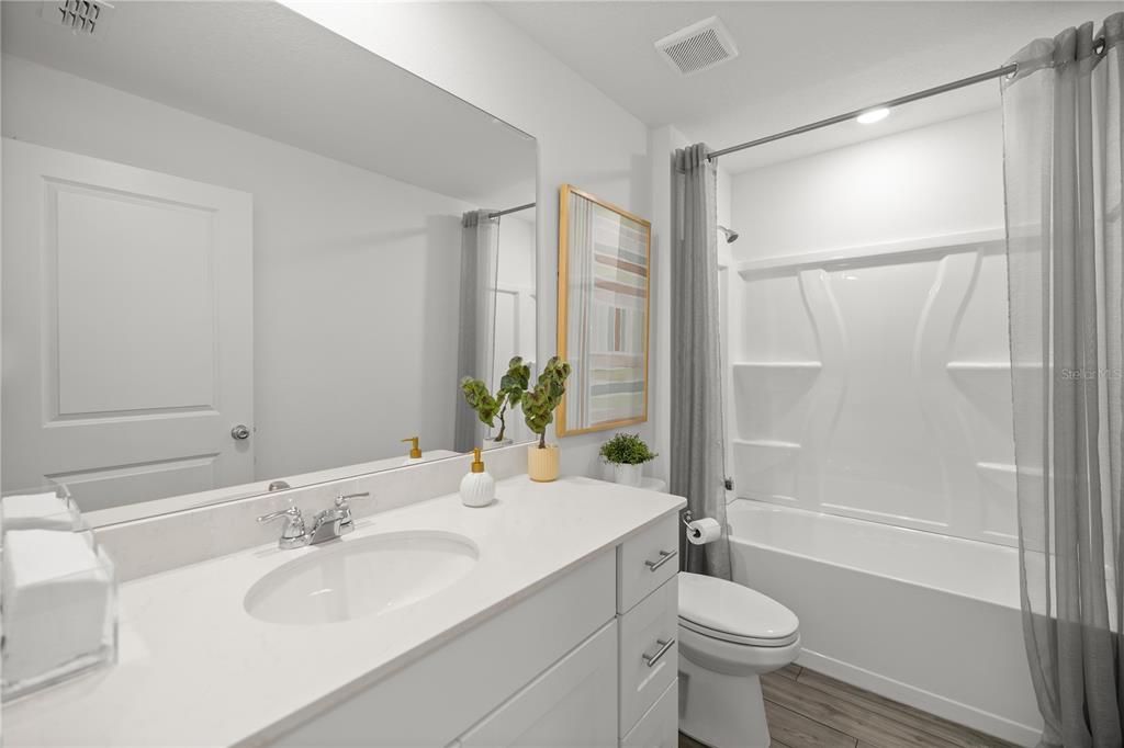 A modern bathroom features a white vanity, a large mirror, and a shower-tub combination — 4239 SW 82ND LANE, OCALA, FL
