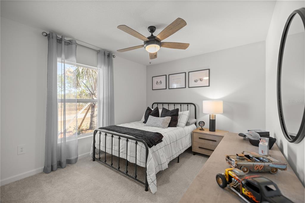 A bedroom features a metal bed frame, a ceiling fan, and a dresser with toys — 4239 SW 82ND LANE, OCALA, FL
