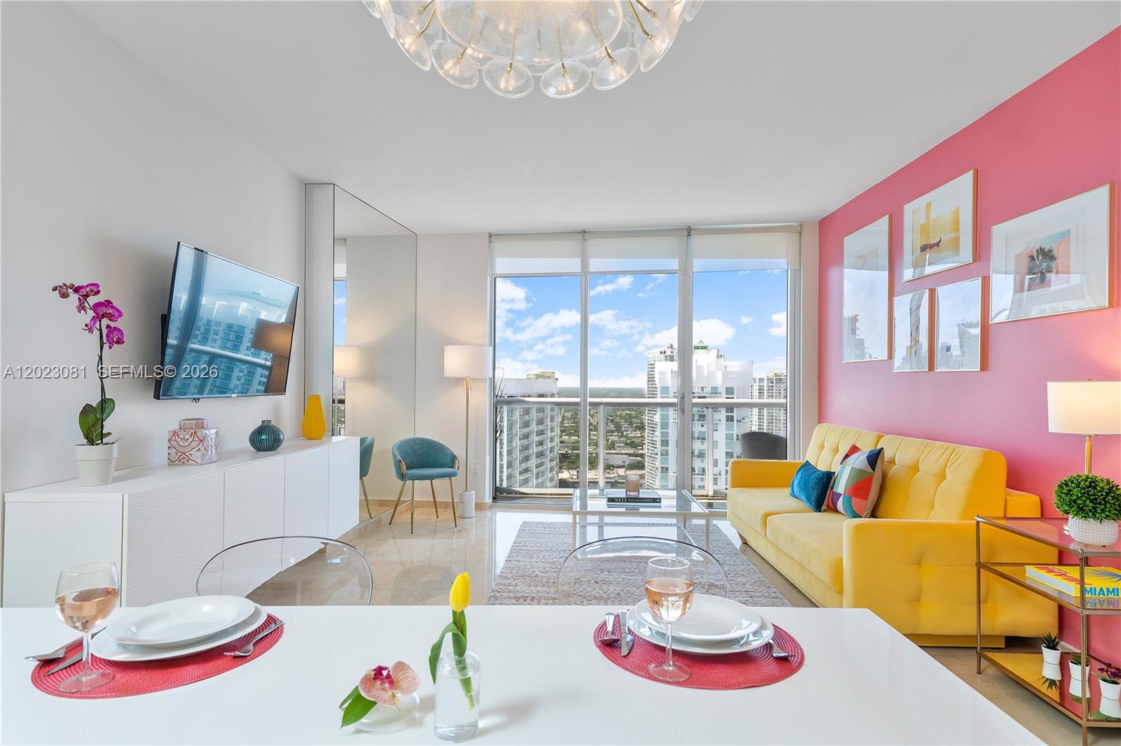 A bright living and dining area features a yellow sofa, pink wall, and balcony view — 485 Brickell Ave # 4206, Miami FL 33131, MIAMI, FL