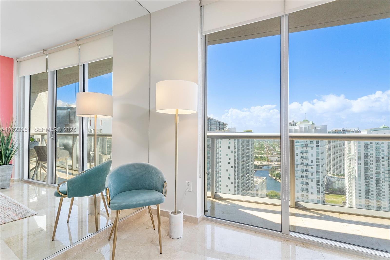 A modern room features a blue velvet chair, a floor lamp, and floor-to-ceiling windows — 485 Brickell Ave # 4206, Miami FL 33131, MIAMI, FL