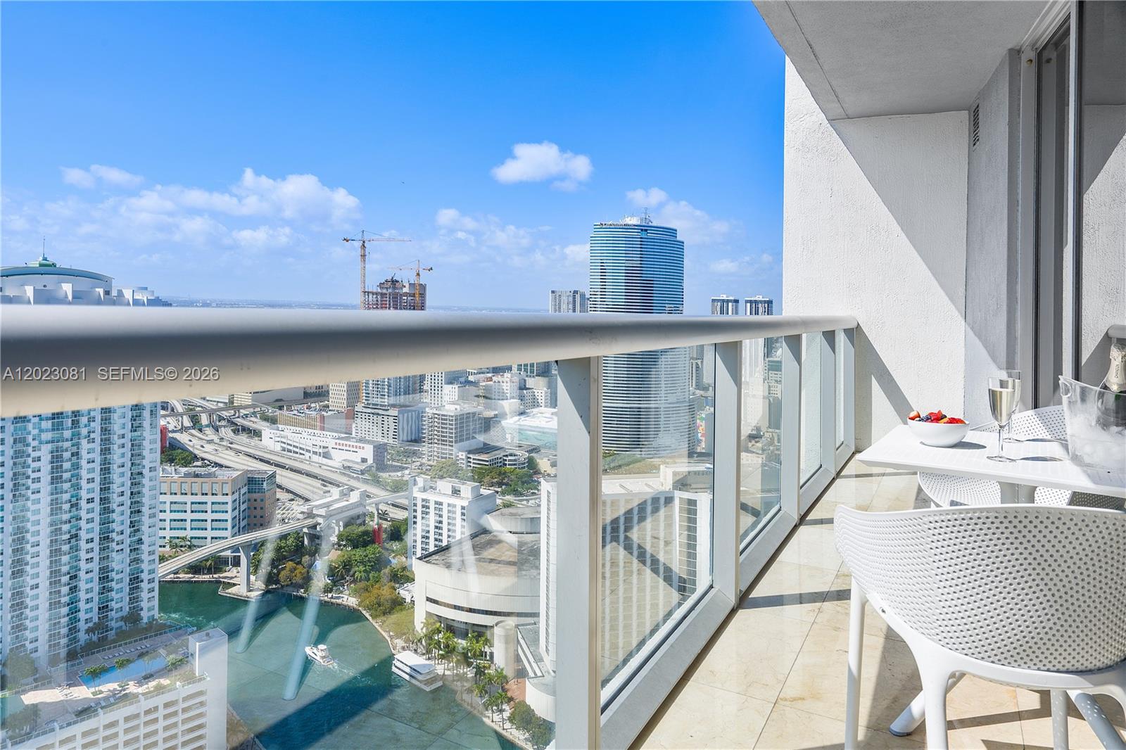 A high-rise balcony overlooks a city skyline, a river, and a construction site — 485 Brickell Ave # 4206, Miami FL 33131, MIAMI, FL