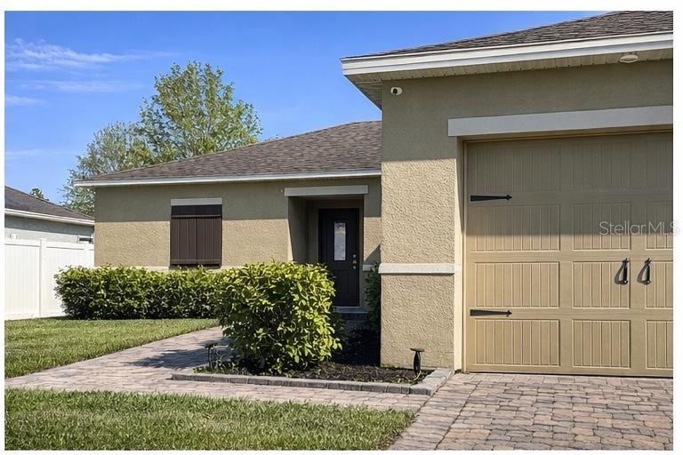 The exterior of a single-story house features a tan stucco facade and a garage — 418 BLUE LAKE CIRCLE, KISSIMMEE, FL