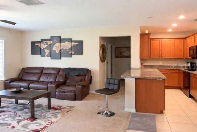 A living room with a brown leather sectional sofa opens into a kitchen with wooden cabinets — 418 BLUE LAKE CIRCLE, KISSIMMEE, FL