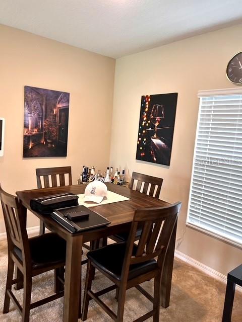 A dining area features a wooden table with four chairs, two wall art pieces, and blinds — 418 BLUE LAKE CIRCLE, KISSIMMEE, FL