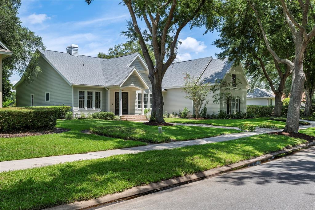 A light gray house with a brick walkway leading to a covered front porch entrance — 6241 BLAKEFORD DRIVE, WINDERMERE, FL