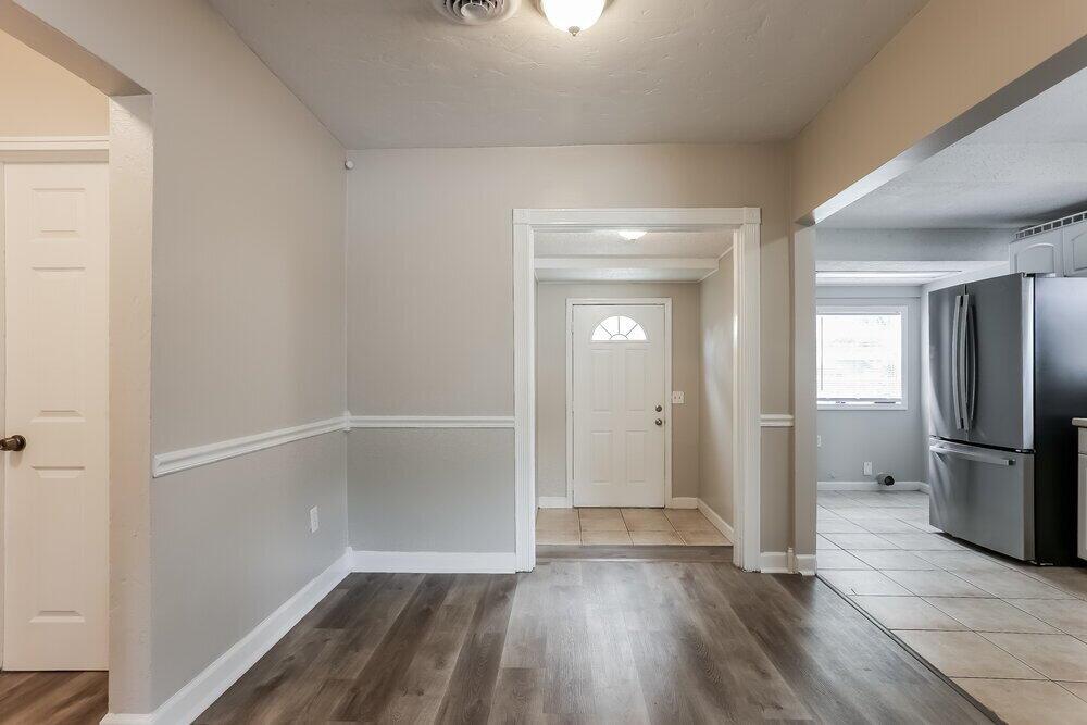 An interior view showing a dining area with wood-look flooring leading to an entryway door — FL