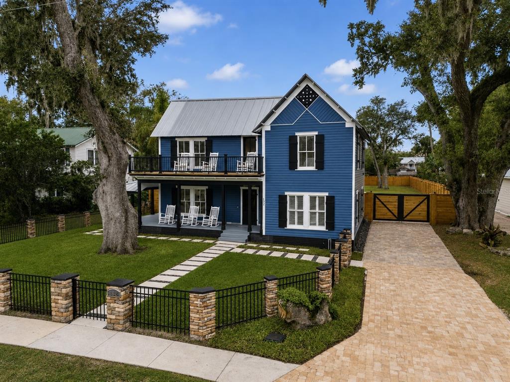 A two-story blue house with a metal roof, front porch, and a stone-pillared fence — 532 FAULKNER STREET, NEW SMYRNA BEACH, FL