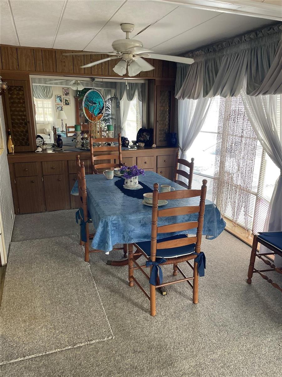 A dining room features wood cabinetry, a mirrored wall, a ceiling fan, and a table — 8621 SW 18th Court, Davie FL 33324, DAVIE, FL