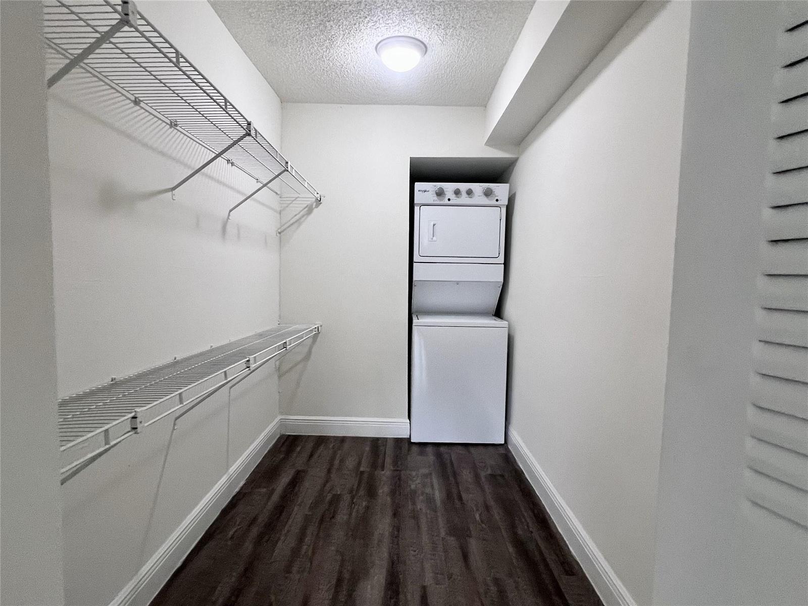 A laundry closet features a stacked washer and dryer, wire shelving, and wood-look flooring — 18335 NW 68 Avenue # 516, Hialeah FL 33015, HIALEAH, FL