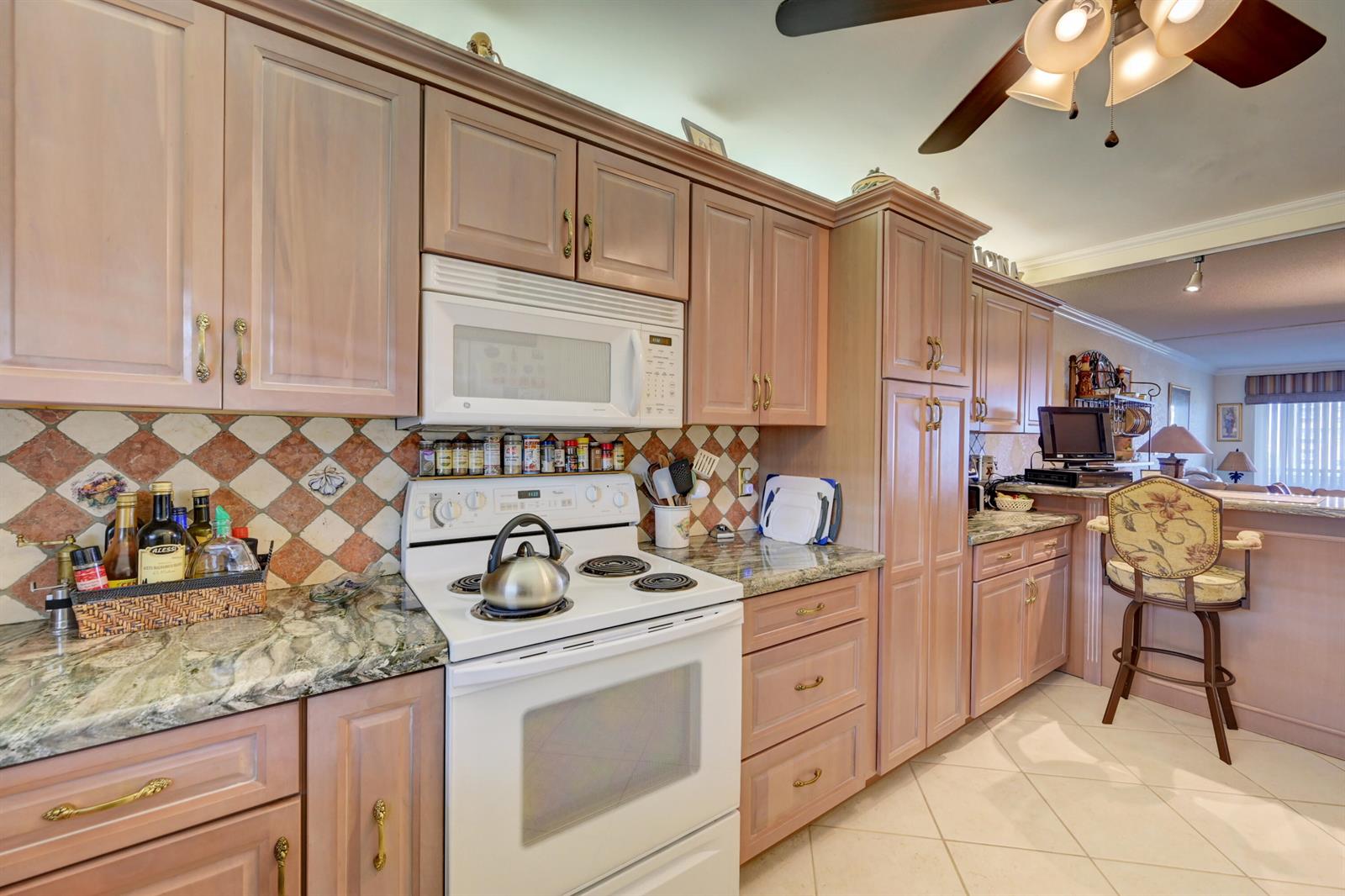 A kitchen with light wood cabinets, white appliances, granite countertops, and a tiled backsplash — 401 Briny Avenue # 708, Pompano Beach FL 33062, POMPANO BEACH, FL