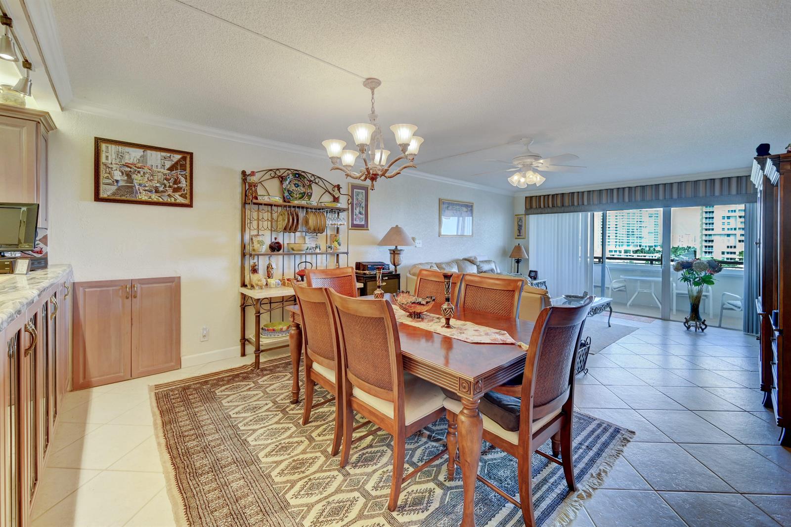 A dining area with a wooden table and chairs sits on a patterned rug — 401 Briny Avenue # 708, Pompano Beach FL 33062, POMPANO BEACH, FL