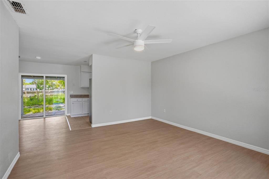 A living room with light wood-look flooring, a ceiling fan, and a sliding glass door — 322 LITTLE ROCK COURT, OCOEE, FL
