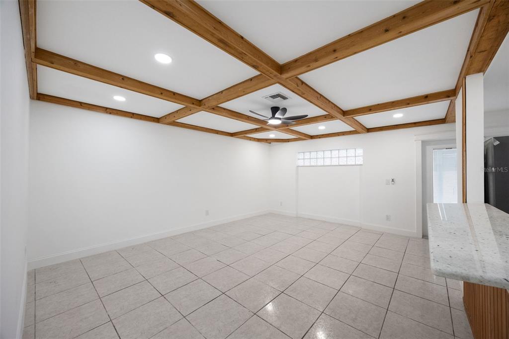An empty room with white walls, tiled floors, and a wooden coffered ceiling — 1010 CLEARMONT STREET, SEBASTIAN, FL