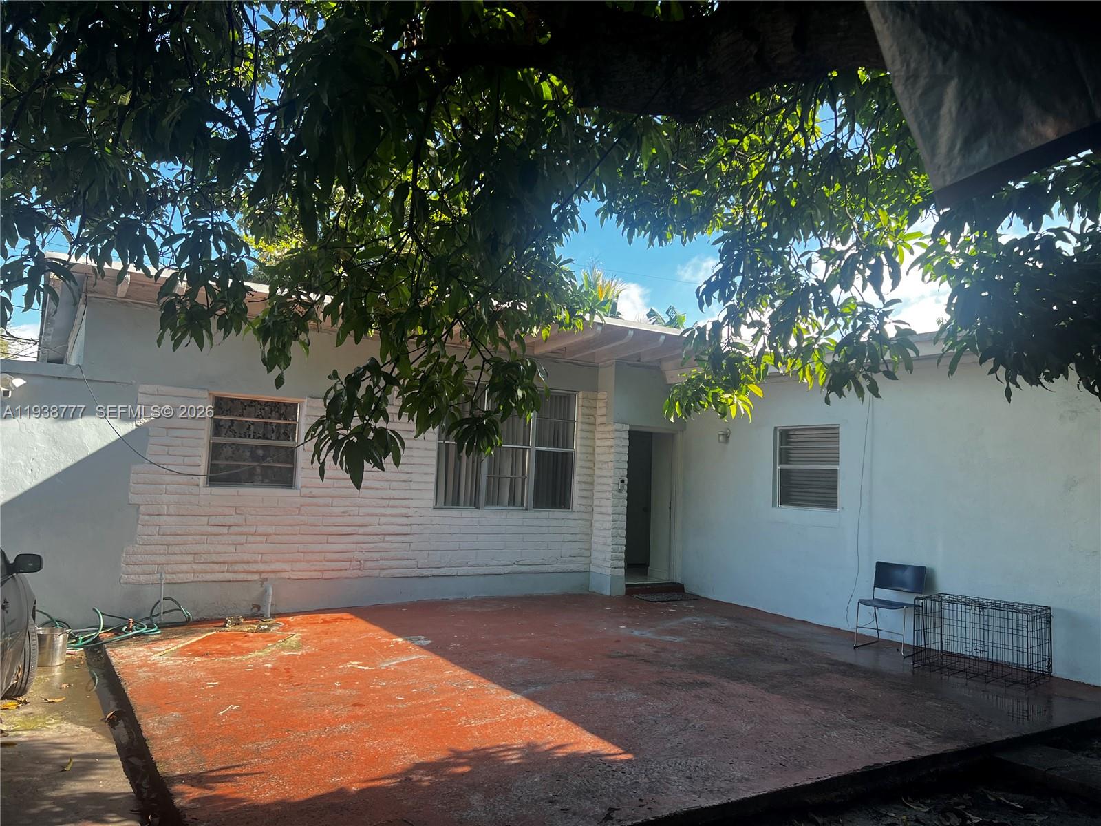 A house exterior features a red concrete patio, white brick accents, and a large tree — 289 NW 109th St, Miami FL 33168, MIAMI, FL