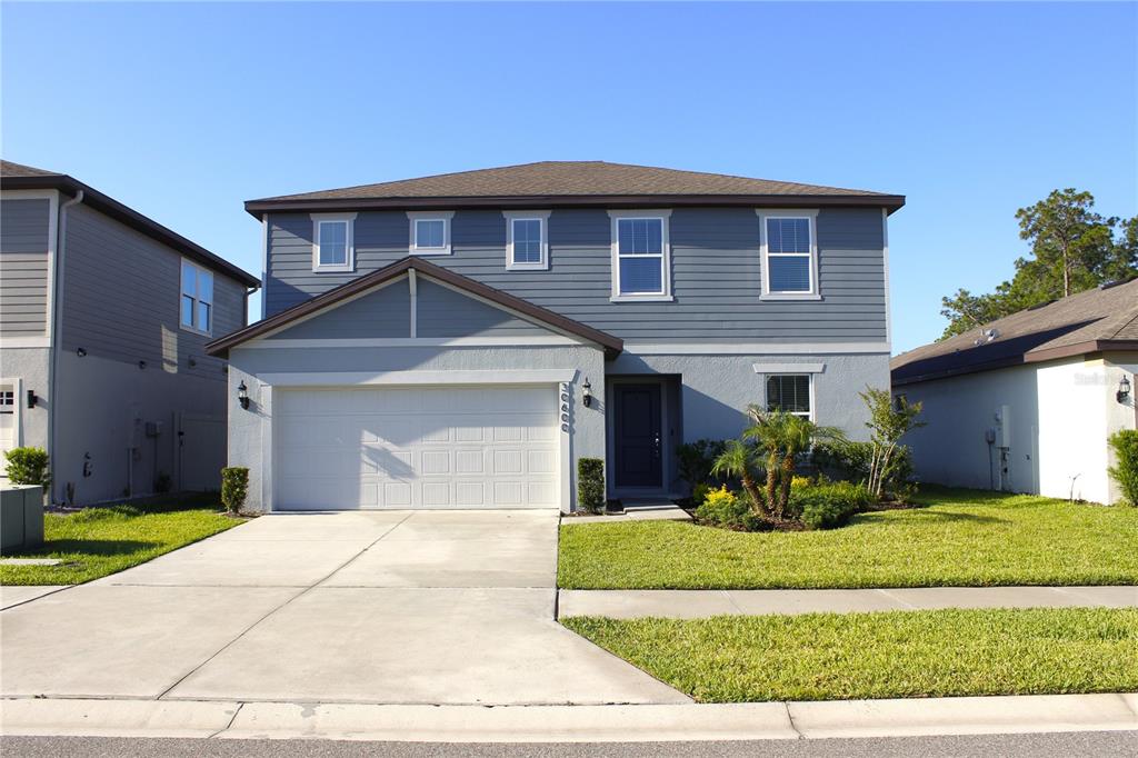 A two-story house with blue siding, a two-car garage, and a front lawn — 30600 THUNDERBIRD DRIVE, WESLEY CHAPEL, FL