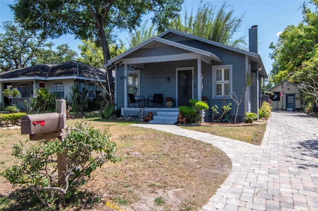 A gray bungalow with a front porch and a paved driveway sits on a grassy lot — 220 W FERN STREET, TAMPA, FL
